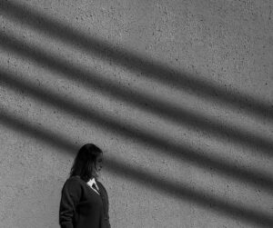 Retrato minimalista de una mujer ante una pared con sombras diagonales