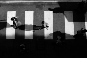 Peatones cruzan un paso de cebra en una escena urbana en blanco y negro