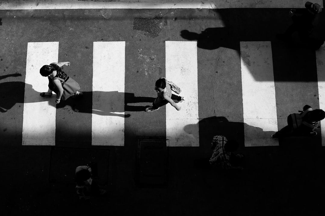 Peatones cruzan un paso de cebra en una escena urbana en blanco y negro