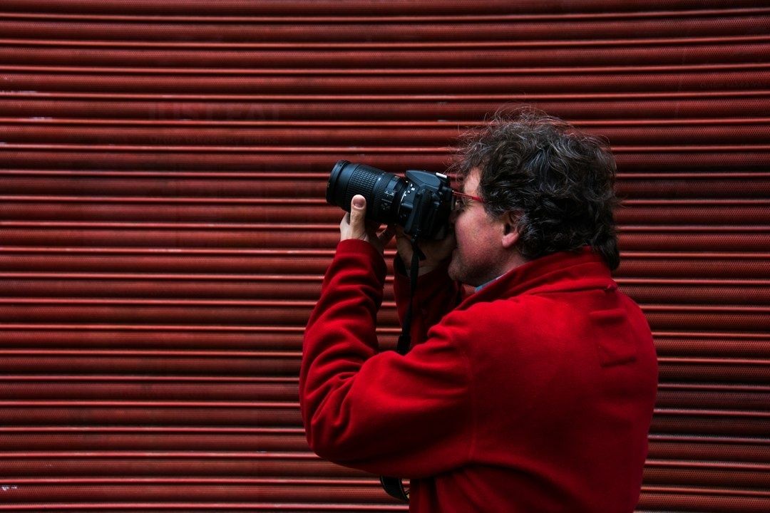 Fotógrafo con cámara frente a una persiana metálica roja